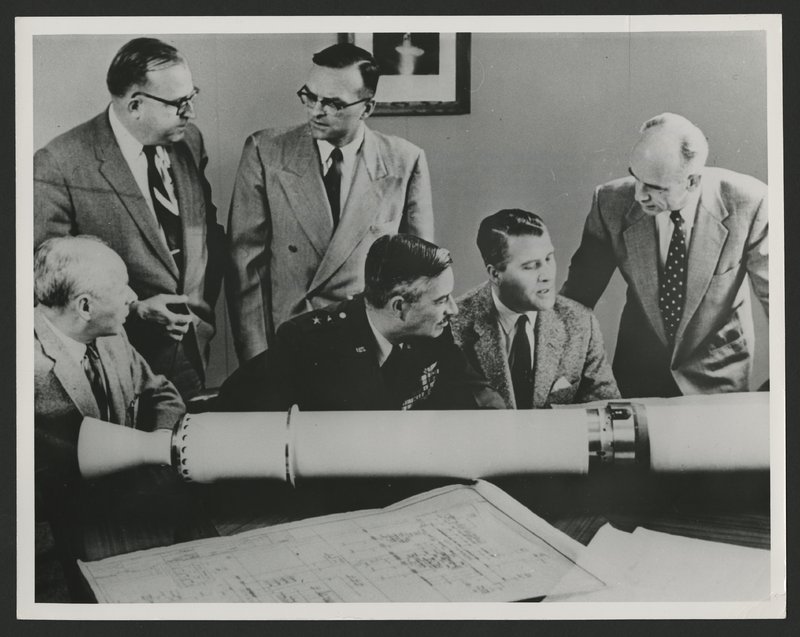 Mr. Eberhard Reese, Major General J.B. Medaris, Dr. Wernher von Braun and Dr. Ernst Stuhlinger (sitting) and Mr. W.A. Mrazak and Dr. Walter Haeussermenn (standing) around the to size prototype model of Explorer I