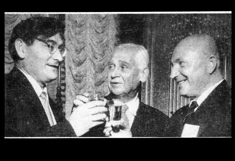 Three Russian men celebrate the successful launch of Sputnik by clinking their glasses together in a toast