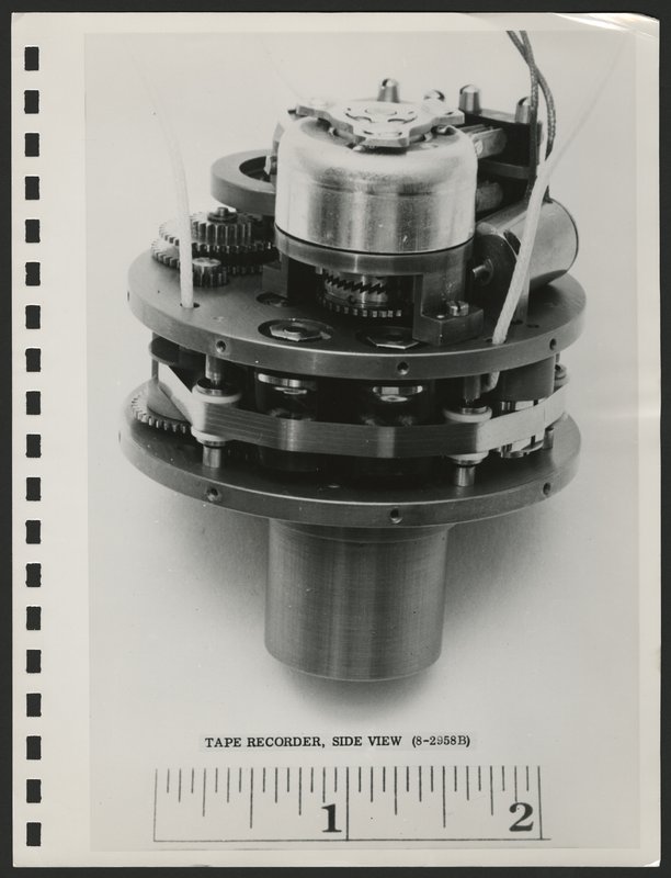 Photograph of Explorer 1 tape recorder from the side with scale. The component is two inches in diameter